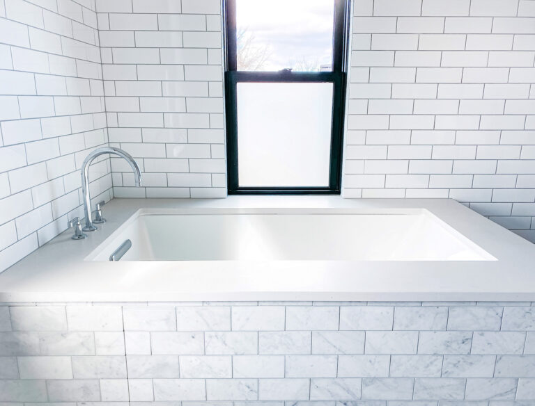 White Bathtub surrounded by White Ceramic Tile.